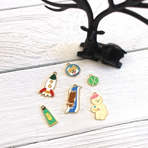 Flat lay of colorful enamel alloy charms with cartoon rocket and dog designs on wood