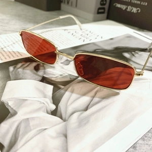 Close-up of retro rectangular metal sunglasses with orange lenses on a magazine