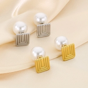Detail of vintage square metal earrings in gold and silver finish with elegant white pearls