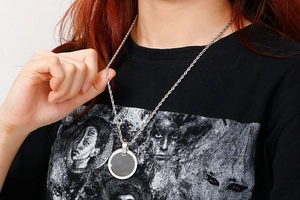 Macro detail of silver twisted chain with a sparkling circular pendant on a model