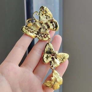 Elegant triple butterfly brooch in gold-tone metal with intricate wing patterns