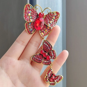 Macro shot of tiered butterfly brooch with red rhinestones and golden alloy finish