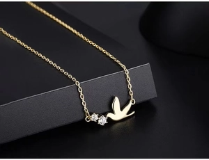 Macro shot of gold bird pendant necklace with sparkling white zircon stone accents