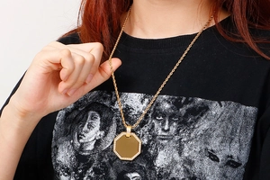 Close-up of a gold-plated octagon pendant necklace with crystal inlay on a model