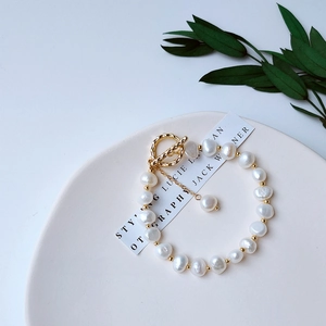 Detailed view of natural baroque pearl bracelet with gold OT clasp on white ceramic tray