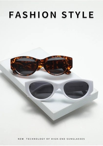 Macro view of retro tortoise shell and thick white oval frame sunglasses on a pedestal