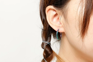 Close-up of iridescent rainbow titanium steel hoop earring worn on female model's ear