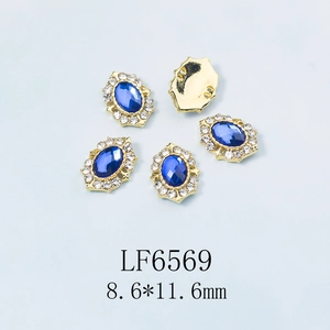 Vue macro de strass bleus ovales pour ongles avec cristaux blancs et base dorée 8,6x11,6mm