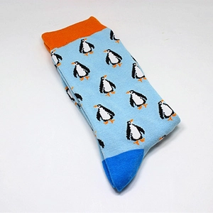 Detailed close-up of blue cotton mid-calf socks with penguin patterns and orange cuffs