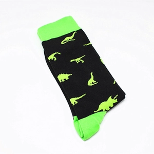 Detail of cotton crew socks featuring green dinosaur patterns and neon accents on black fabric