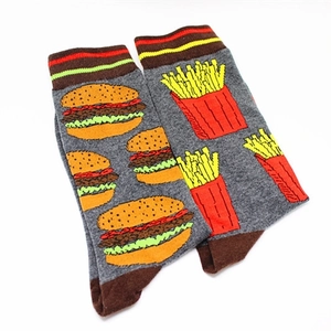 Detail of creative mismatched socks featuring burger and fries embroidery on grey cotton