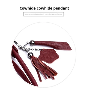 Detailed view of a genuine cowhide leather tassel charm in deep red with metallic chain