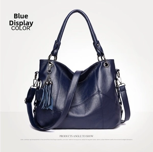 Detail of blue textured leather bag with heart tassel charm and adjustable shoulder strap