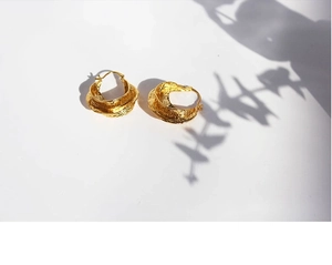 Detail of gold hoop earrings with irregular hammered texture and organic lava finish