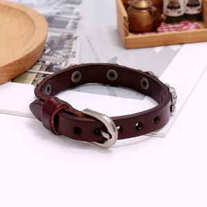 Macro detail of dark brown leather punk bracelet with silver skull rivets and metal buckle