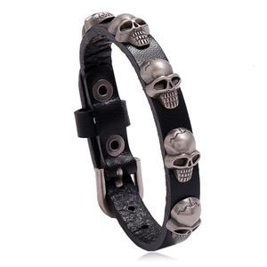 Punk style black leather bracelet with metal skull charms and adjustable pin buckle
