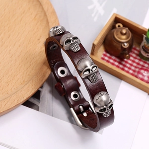 Macro detail of punk brown leather bracelet with silver metal skulls and adjustable buckle