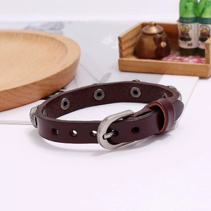 Detailed shot of brown leather punk bracelet with metal rivets on a wooden tray