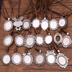 Antique silver DIY oval pendant trays with brown PU cords on dark wood surface