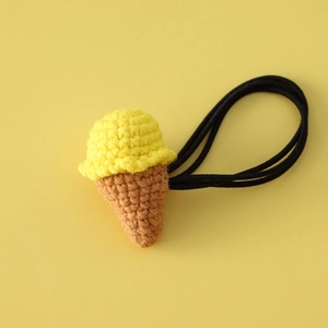 Macro detail of hand-crocheted ice cream hair tie with yellow knitting and black elastic