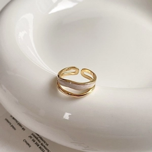 Close-up of double-layered gold ring with zircon squares and wavy band on ceramic plate