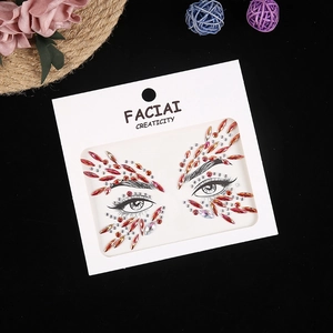 Macro detail of red and pink acrylic face jewels on packaging for festival makeup