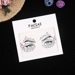 Macro shot of iridescent acrylic resin face gems and crystal eye stickers on white card