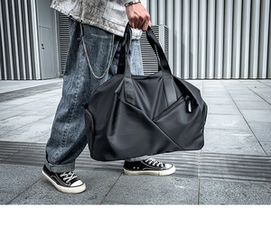 Modern black nylon gym bag with dry-wet separation carried by hand in urban street setting