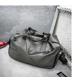 Detail of grey sports bag featuring dual handles and a detachable shoulder strap on a grey background