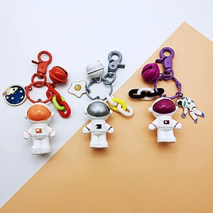 Detailed view of astronaut keychains with colorful bells and space charms in three colors