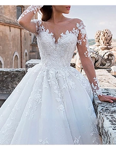 Close-up of elegant V-neck lace neckline and sheer long sleeves on an ivory wedding gown