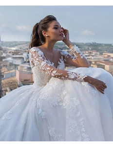 Close-up of sheer lace long sleeves with 3D floral embroidery on white wedding dress