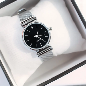Macro detail of the silver mesh strap and black quartz dial inside a gift box