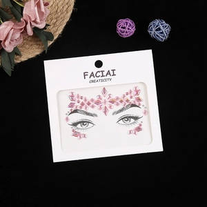 Detailed view of pink diamond-shaped face rhinestones on white card with floral accents