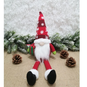 Dettaglio di uno gnomo di Natale in peluche con cappello a righe e scatola regalo