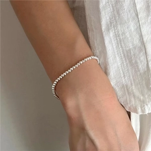 Minimalist 925 sterling silver beaded bracelet on wrist with elegant silver metal texture