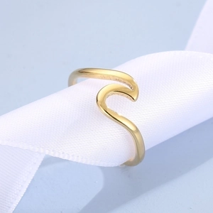 Detailed close-up of a wavy gold stainless steel adjustable ring on a white woven ribbon