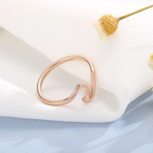 Close-up of minimalist rose gold wave ring on white fabric and light blue texture