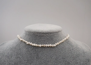 Close-up of white Baroque freshwater pearls on a gray jewelry display stand