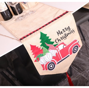 Close-up of Christmas table runner with gnome print, red truck, and tassel detail