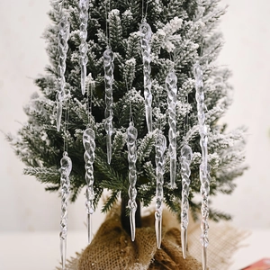 Set of transparent spiral icicle ornaments hanging on a snowy Christmas tree