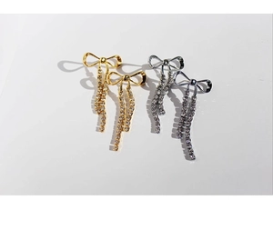 Detail view of sparkly rhinestone bow earrings with tassels in gold and silver finish