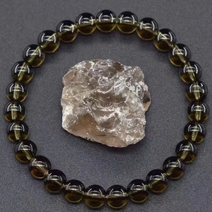Detail of dark brown crystal beaded bracelet with natural raw gemstone on textured grey surface