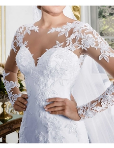Détail de robe de mariée blanche avec manches en dentelle florale et décolleté transparent
