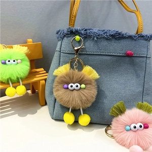 Close-up of cute plush doll keychains in various colors hanging on a blue denim bag