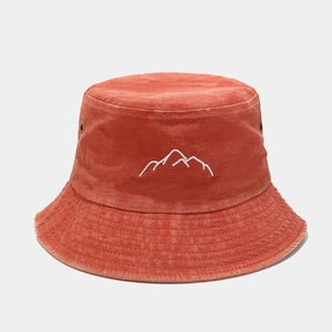 Macro detail of mountain peak embroidery on washed brick red cotton bucket hat