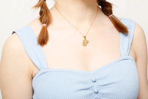 Gros plan d'un collier doré avec pendentif chiot porté par un mannequin en bleu