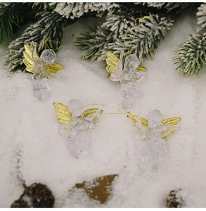 Detailed view of four clear acrylic Christmas angels with gold wings on snowy pine branches