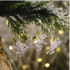 Close-up of four transparent acrylic angel ornaments with gold wings on a snowy branch