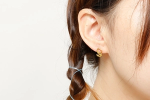 Gros plan de boucles d'oreilles cœur dorées minimalistes portées par un mannequin